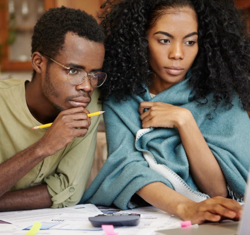 young-african-wife-husband-with-many-debts-doing-paperwork-together-analyzing-expenses-planning-family-budget-calculating-bills-sitting-kitchen-table-with-laptop-calculator-papers-min